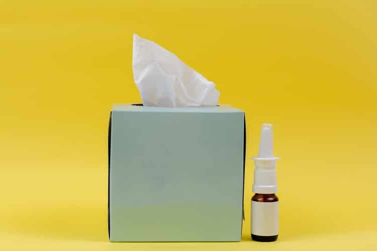 A box of tissues and bottle of nasal spray.