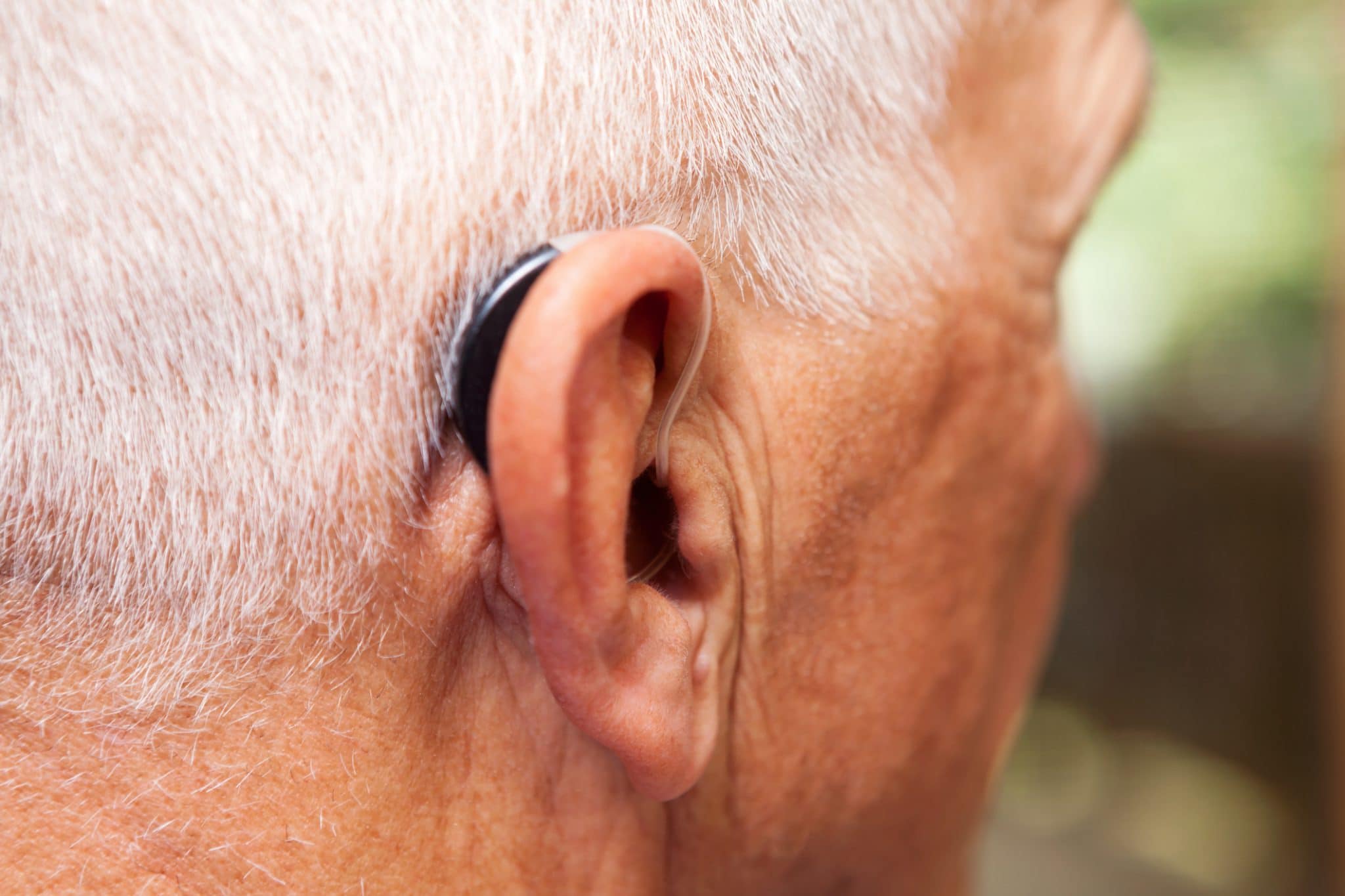 Close up of man wearing a behind-the-ear hearing aid.