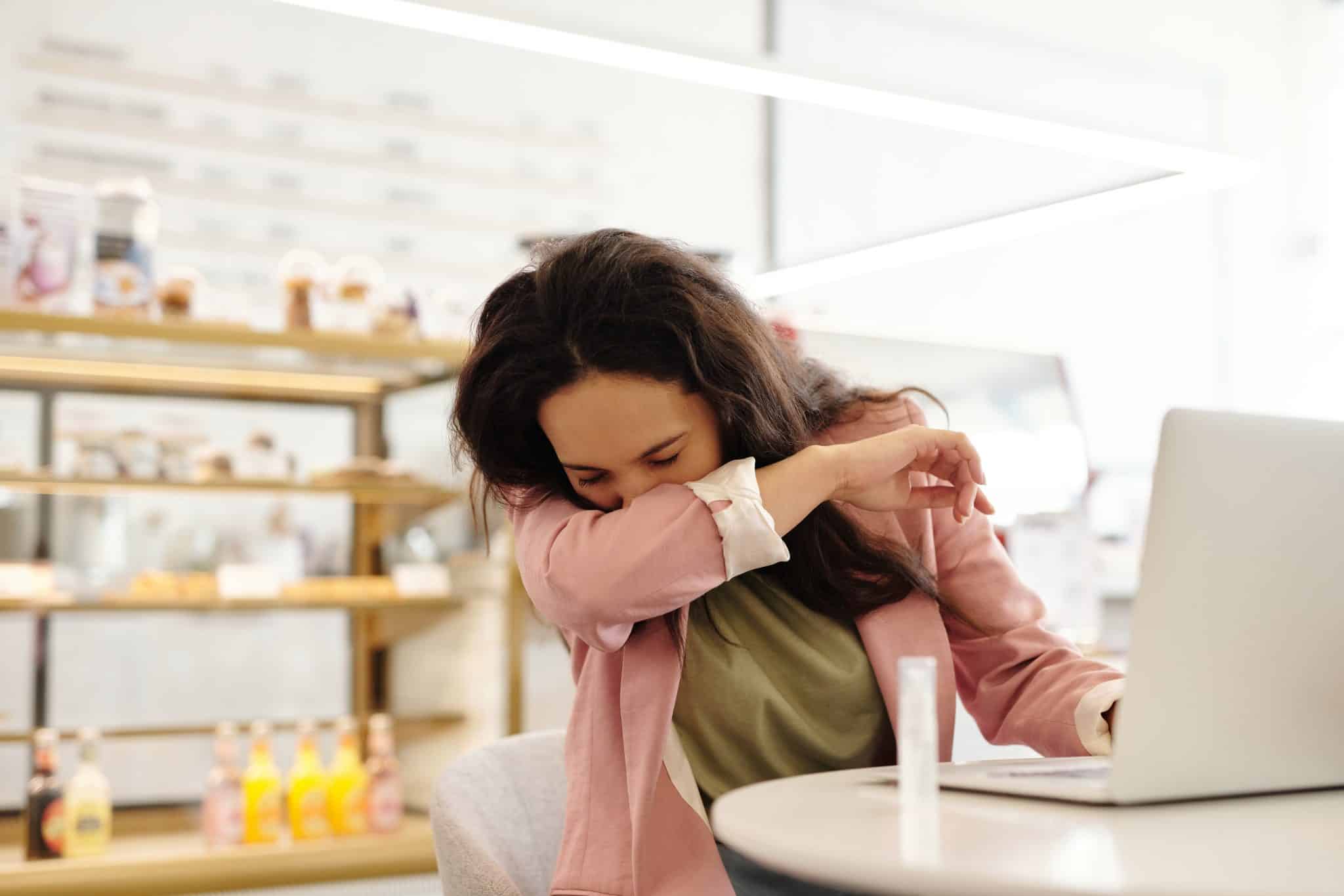 Woman covering her nose during sneeze.