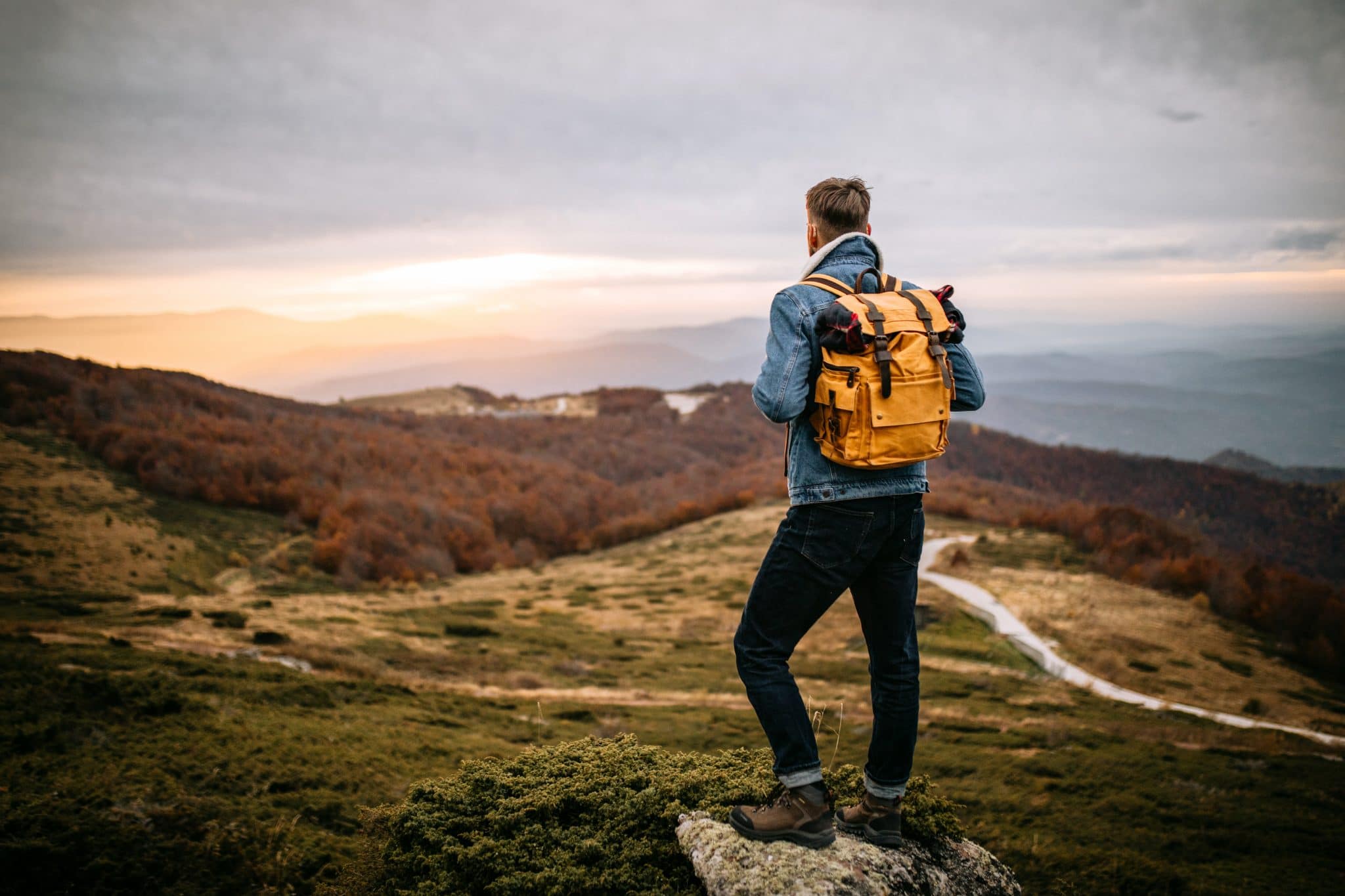 A hiker standing on a cliff edge and looking over the horizon.
