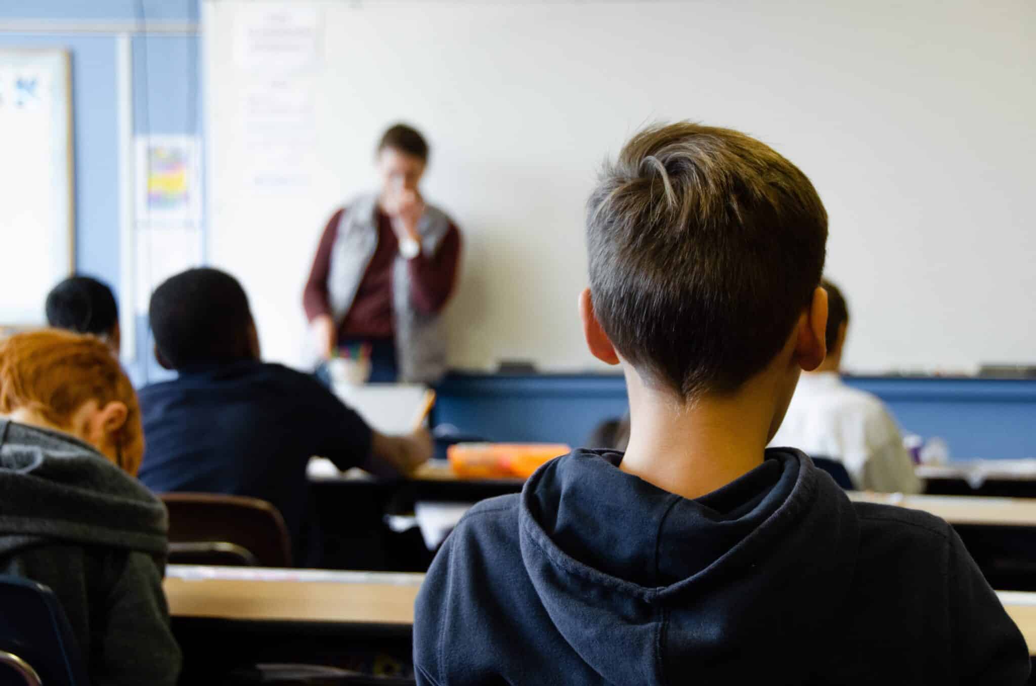 Students listening to a teacher in a classroom environment.