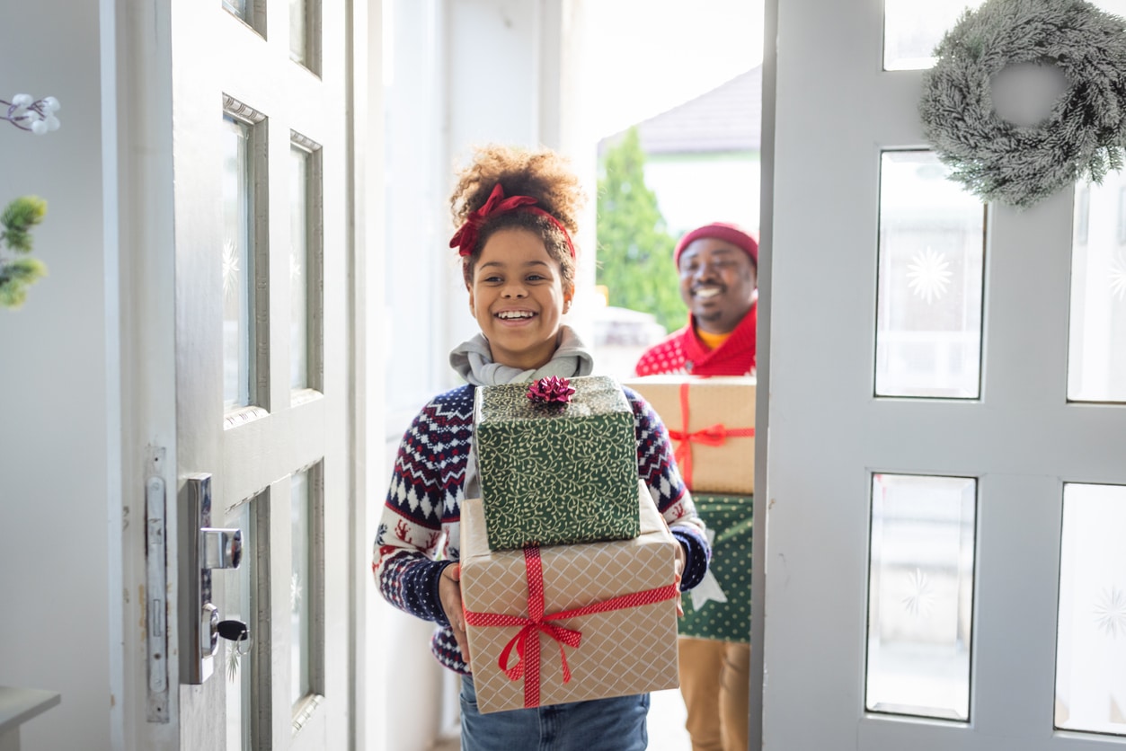 Young girl and her dad coming home with Christmas presents.