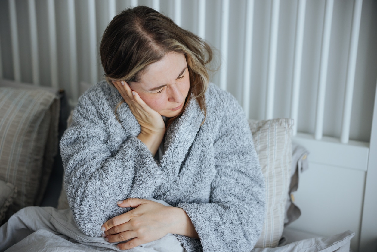 Woman with ear pain holds ear
