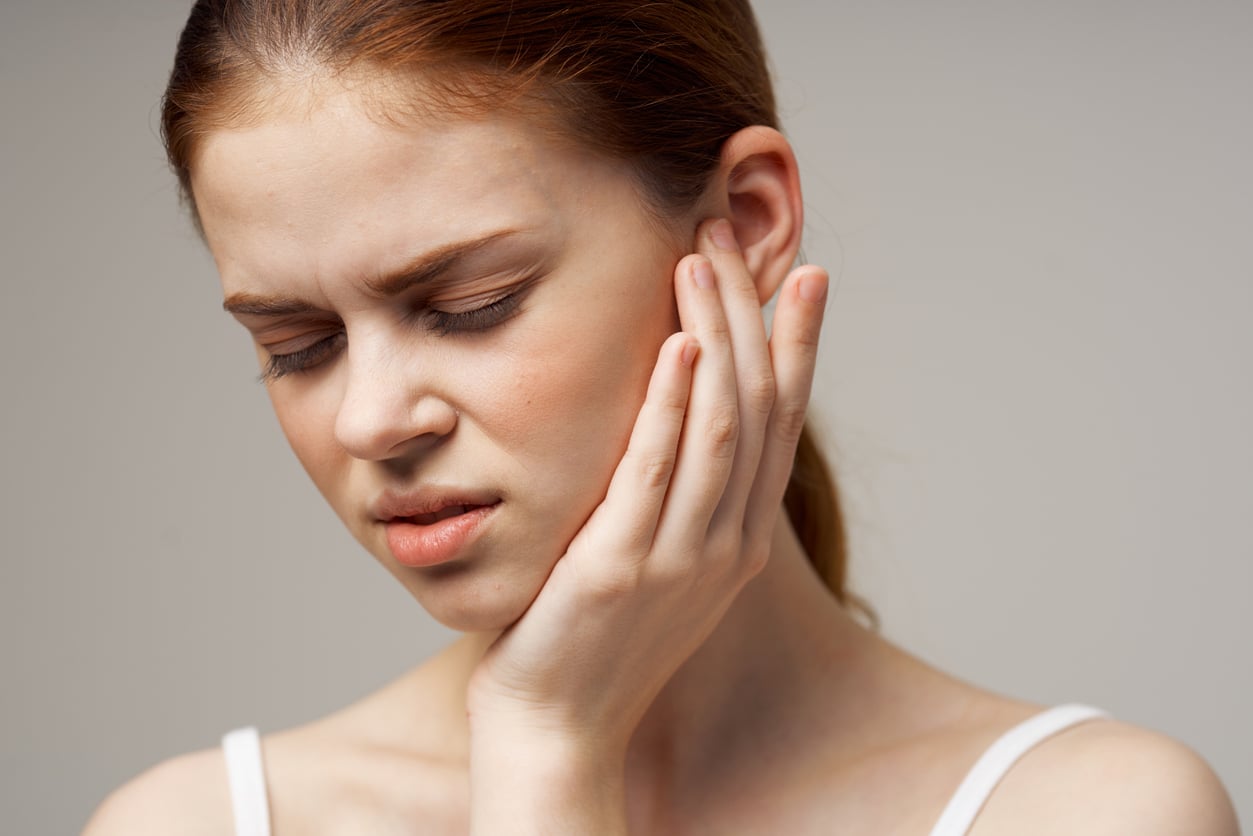 Woman with ear pain holds ear