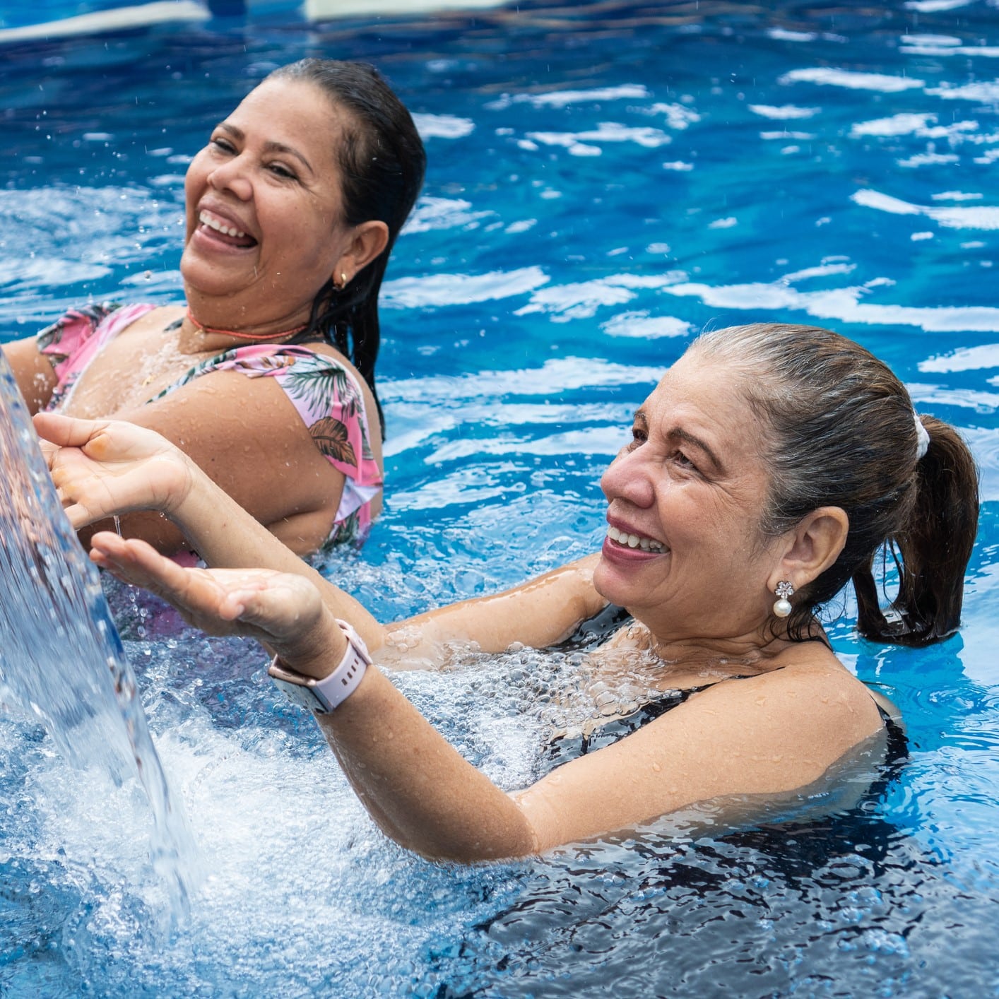Two women swimming and playing in the water.
