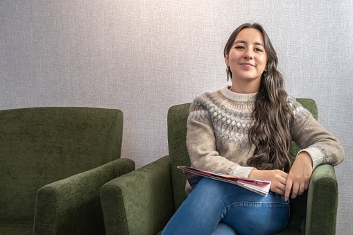Smiling person in a waiting room before her first hearing evaluation.