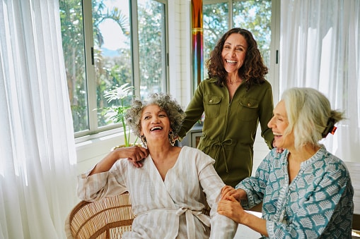 Friend group of women smiling in a well-lit room.