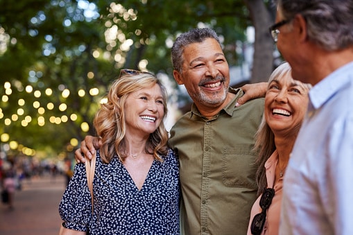 Group of happy friends with their arms around each other and laughing in a park